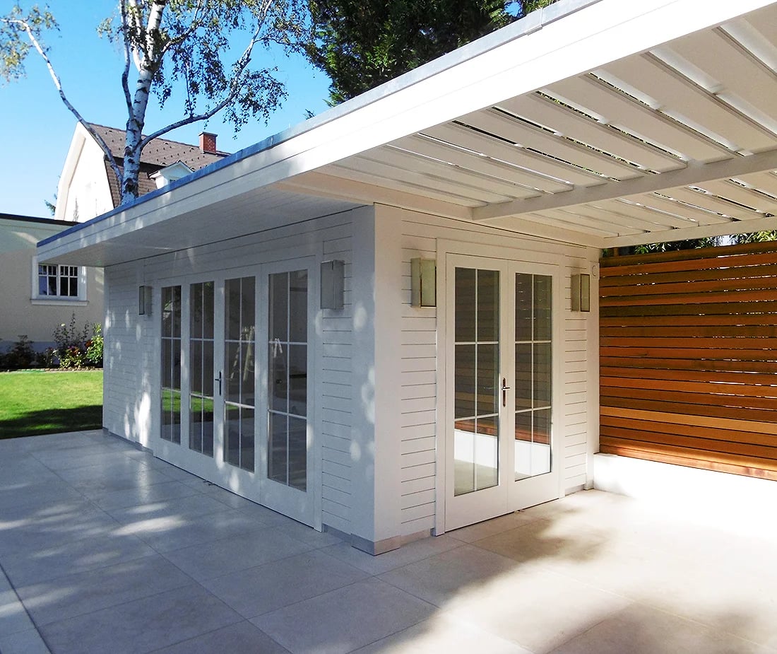 Weißes Poolhaus aus Holz mit Pergola im Garten